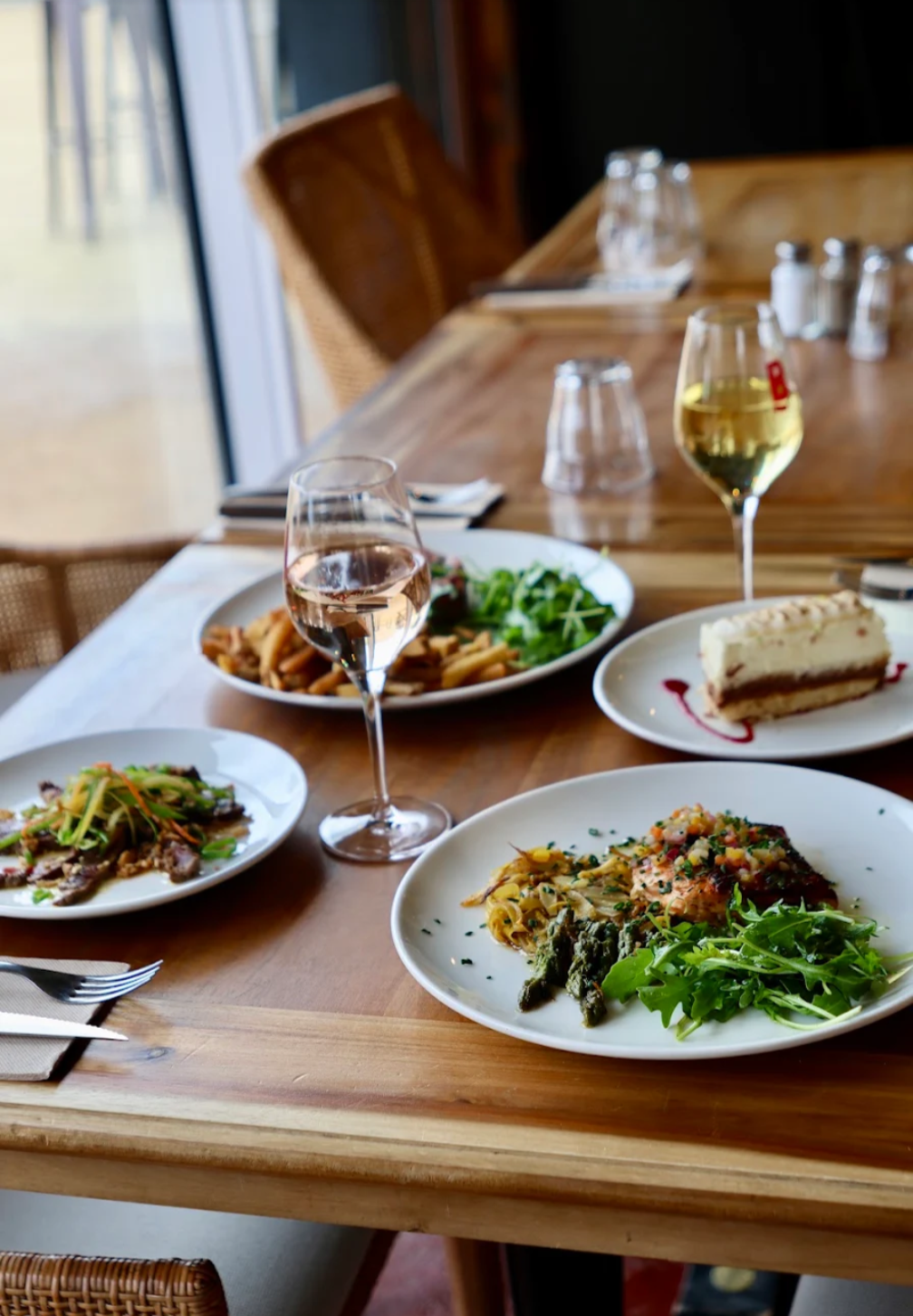Table dressée près de la vitre : plats, dessert et verre de vin