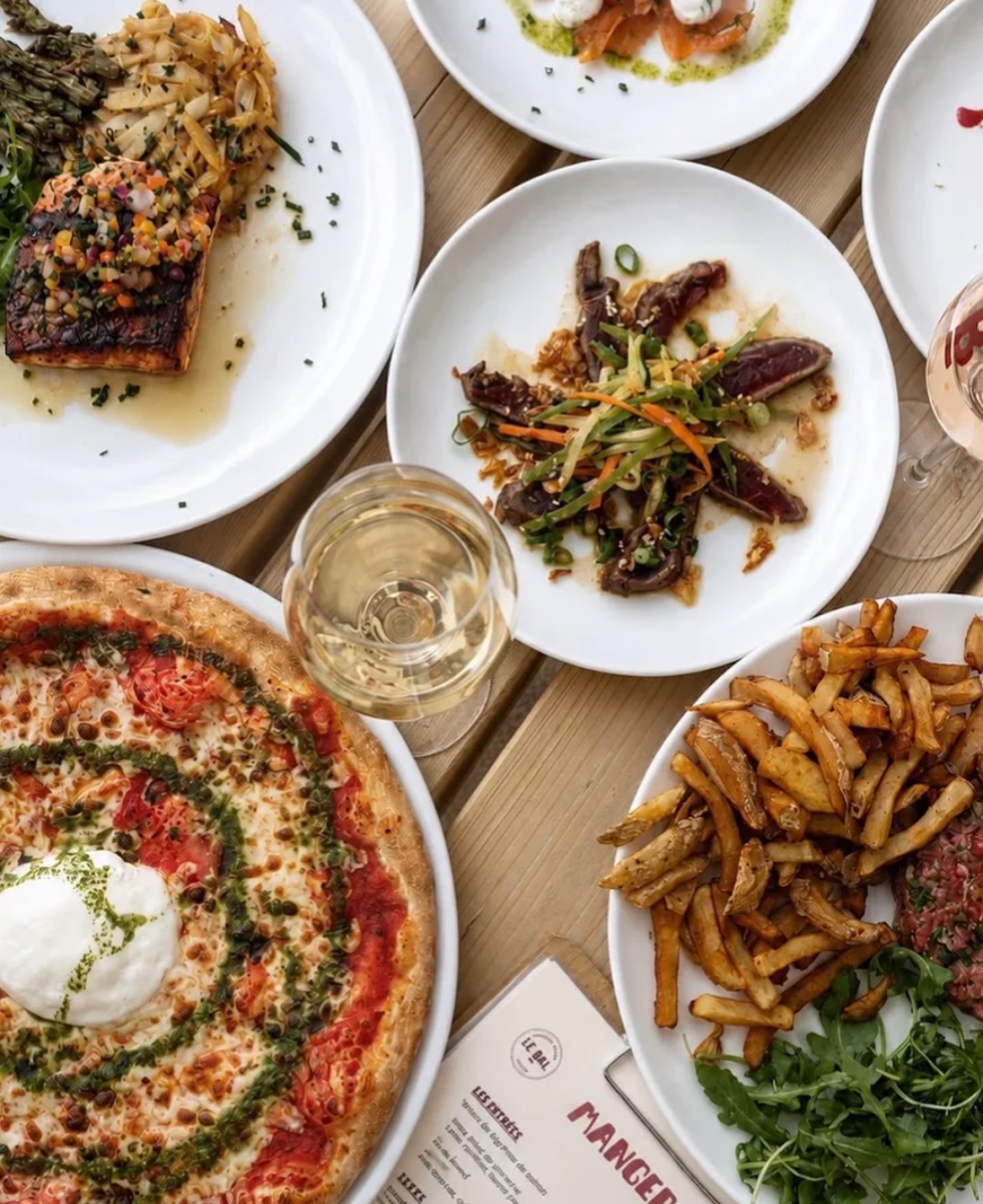 Vue de dessus de plusieurs assiettes du Bal : saumon, tartare, pizza burrata et frites